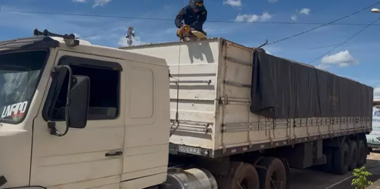 A imagem em destaque mostra um policial rodoviário federal inspecionando o caminhão que transportava a carga de madeira. (Foto: Divulgação | Ascom PRF)